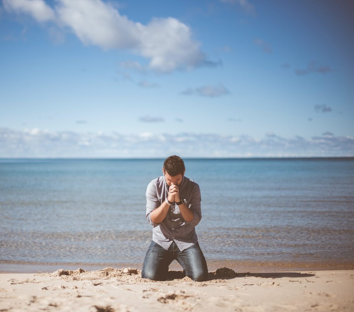 man kneeling down near shore