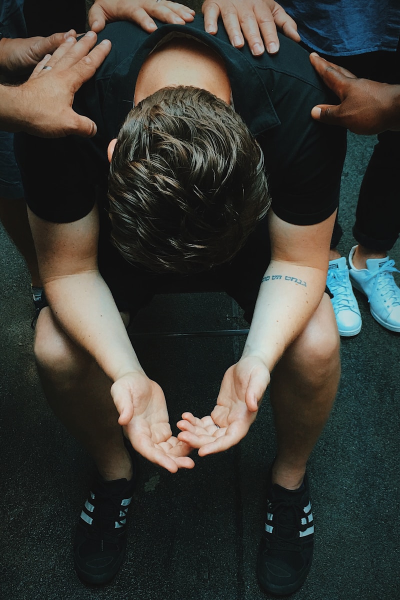 man sitting on chair holding and surrounded by people