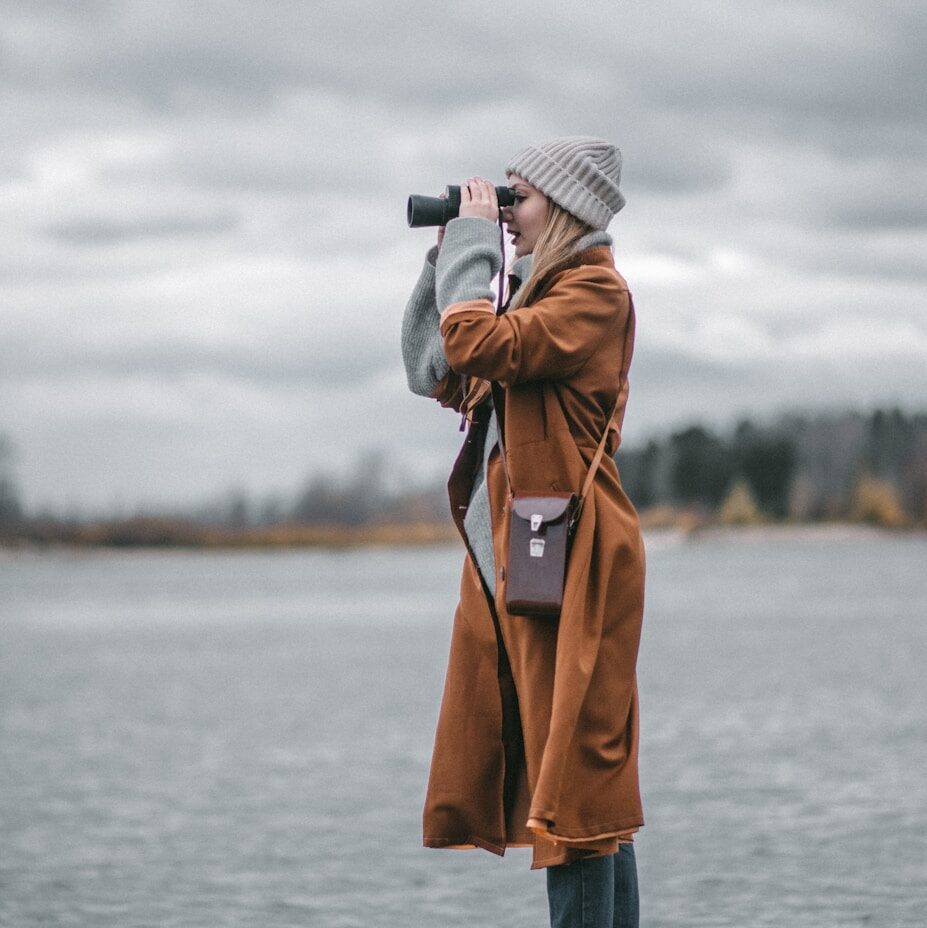 a person with a camera on a rock by water